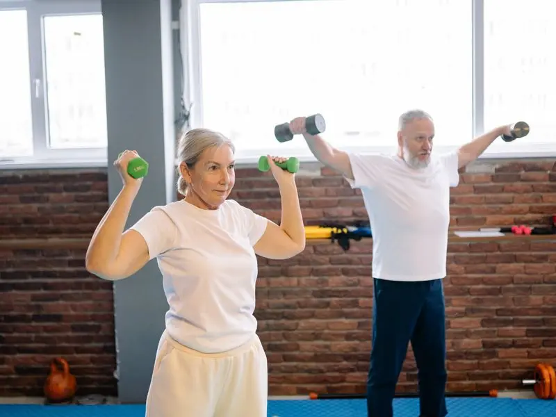 Couple senior haltères gym — suivi coaching personnalisé sport-santé